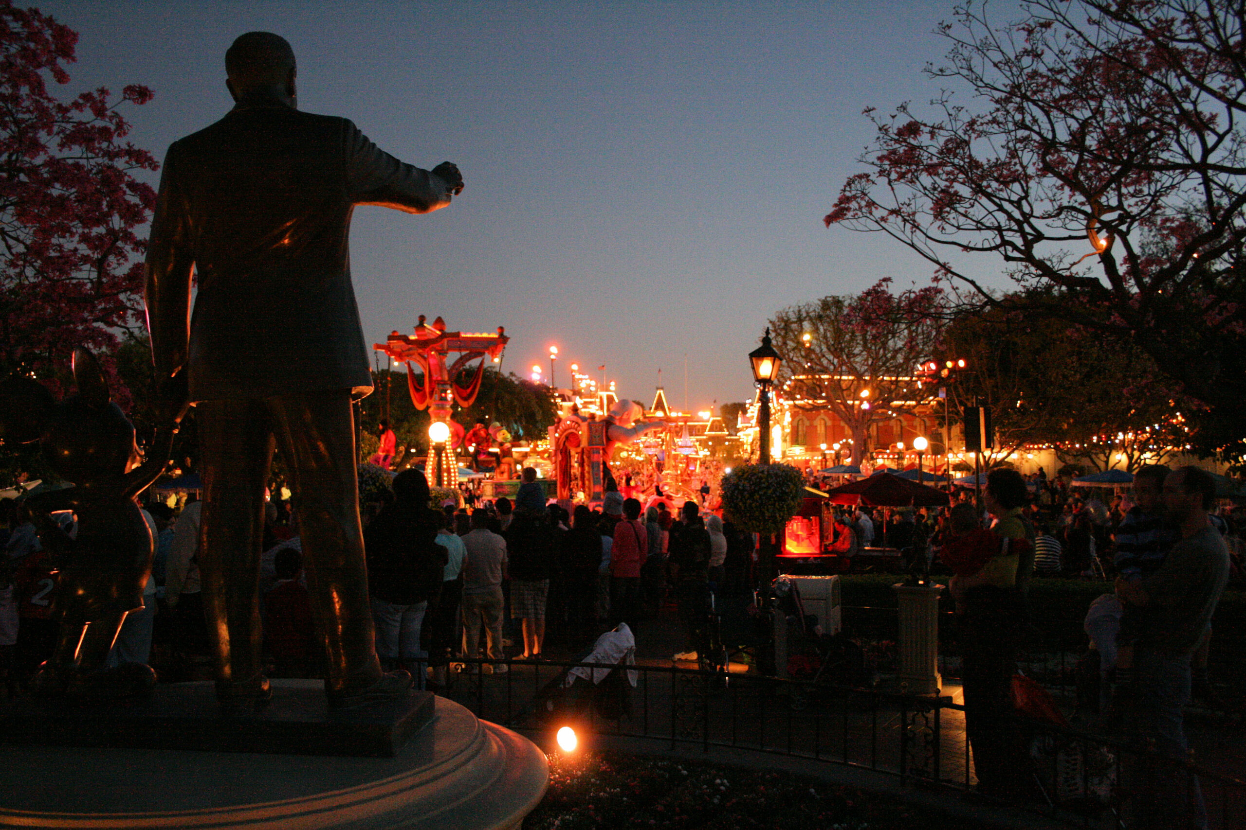 Disneyland at night as seen from behind the statue of Walt Disney and Mickey Mouse near Main Street