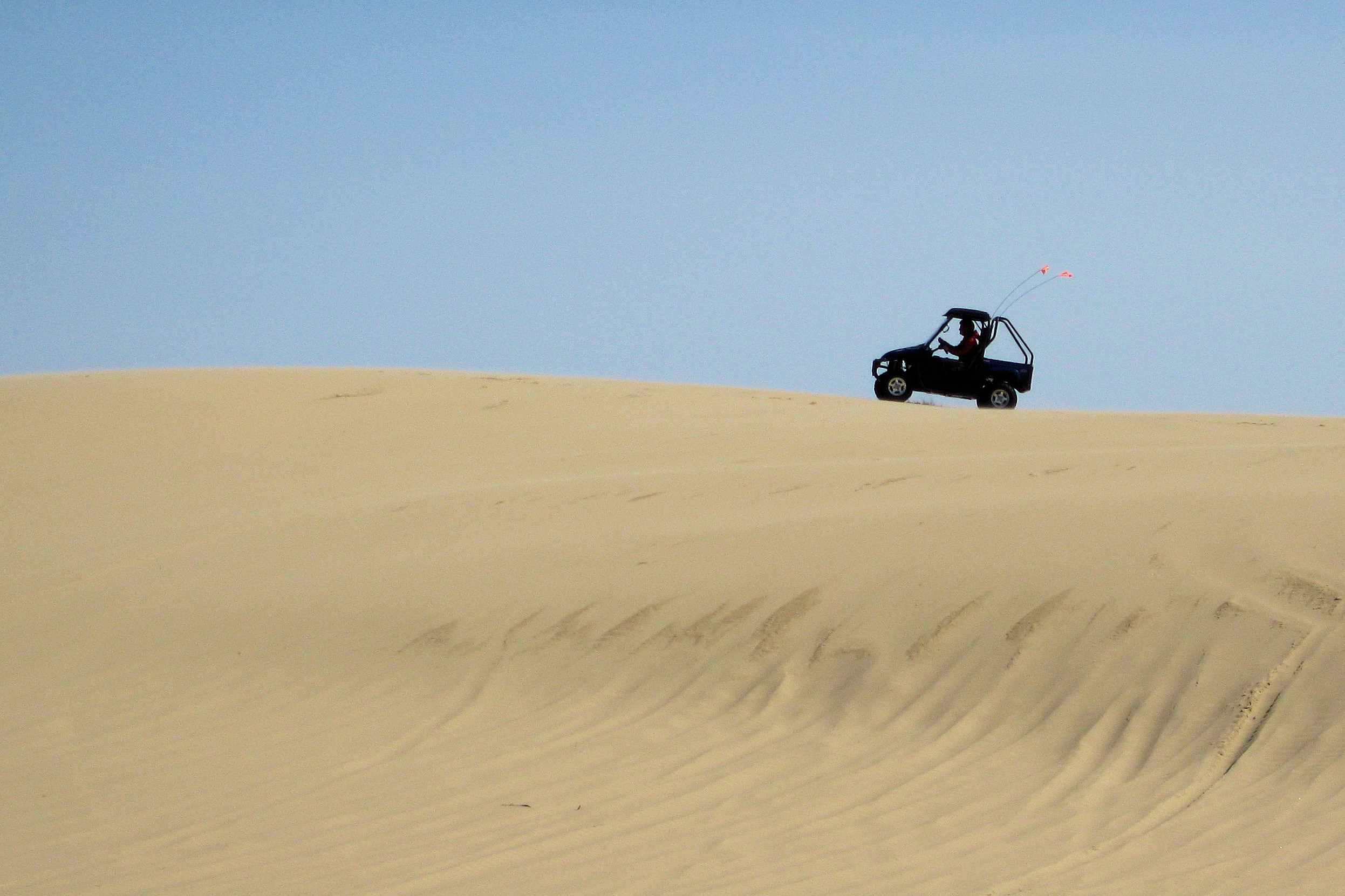 A traveler pilots a Yamaha Rhino across a sand dune in southern Oregon.