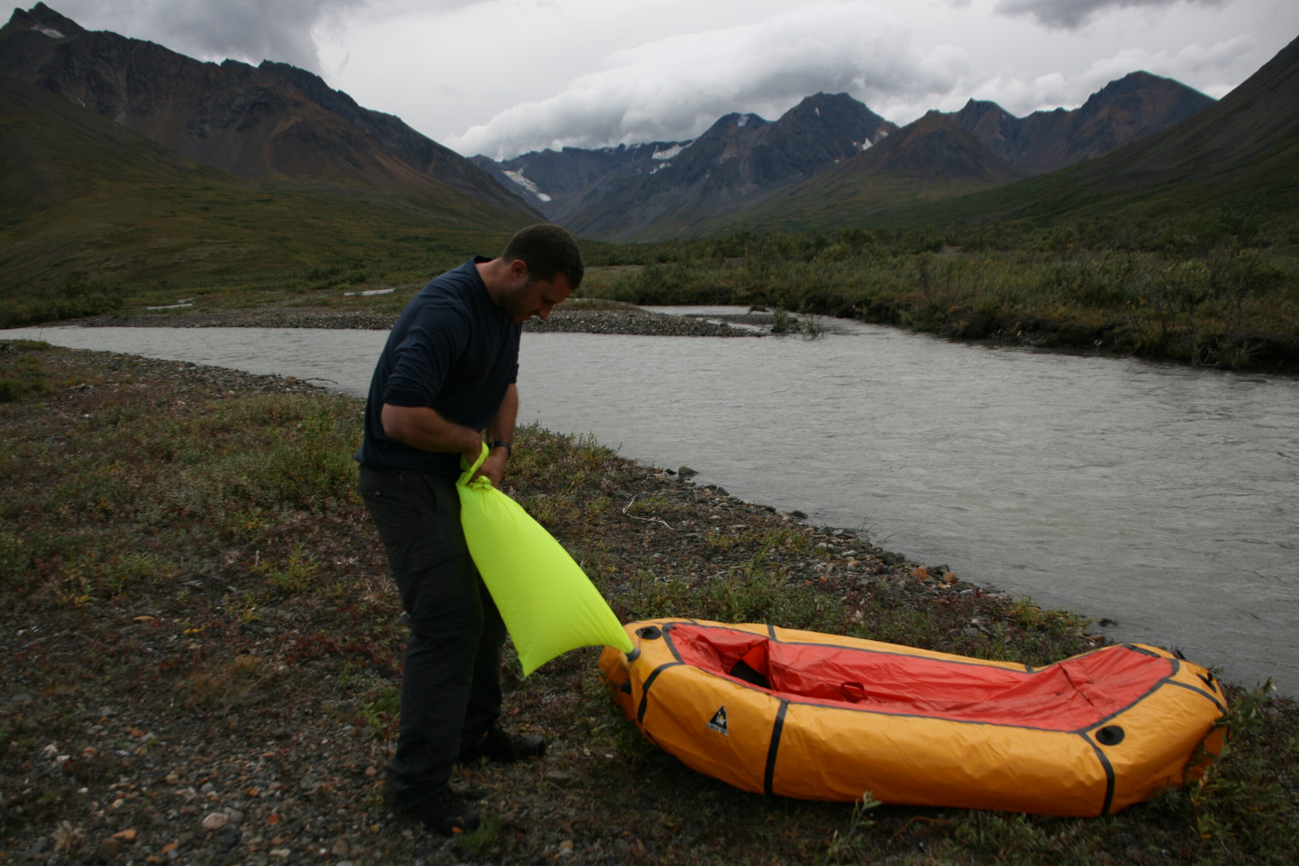 Hank inflates a packraft on the shore of Denali's Sanctuary River.