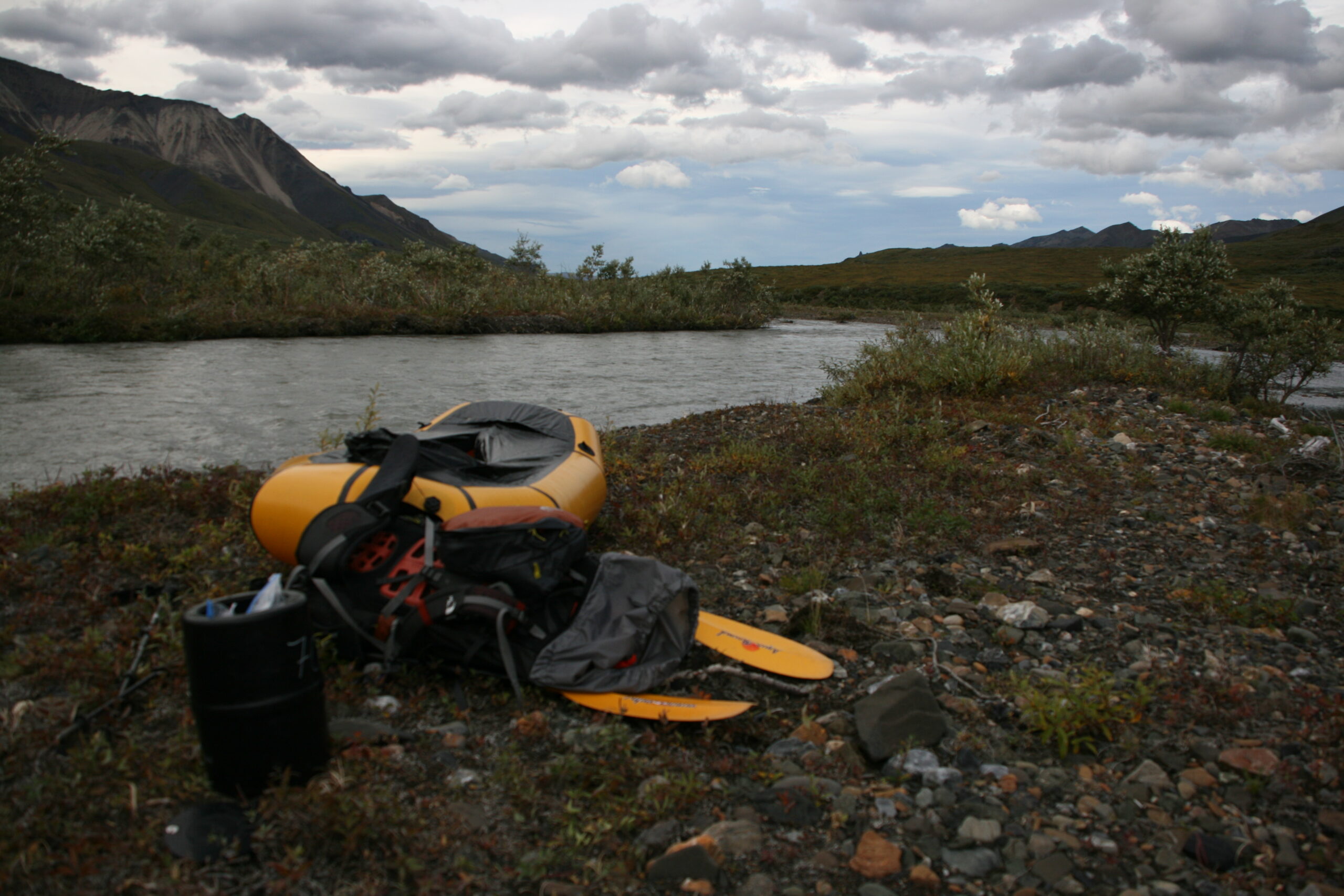 A packraft, a boat light enough to be carried in a backpack, sits on the edge of Sanctuary River in Denali National Park, Alaska.
