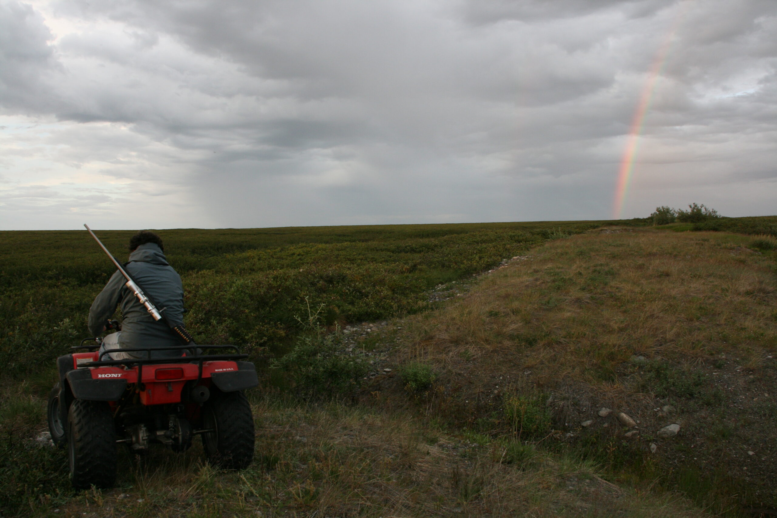A rainbow appears in the arctic sky above an ATV.