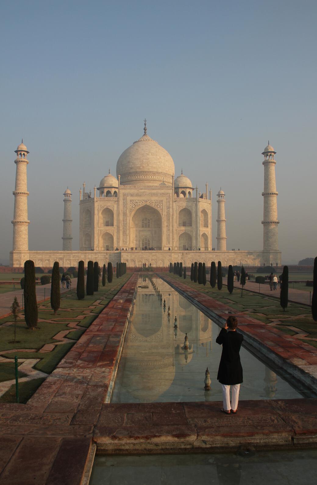A woman photographs the Taj Mahal from the tip of the garden's reflection pool.