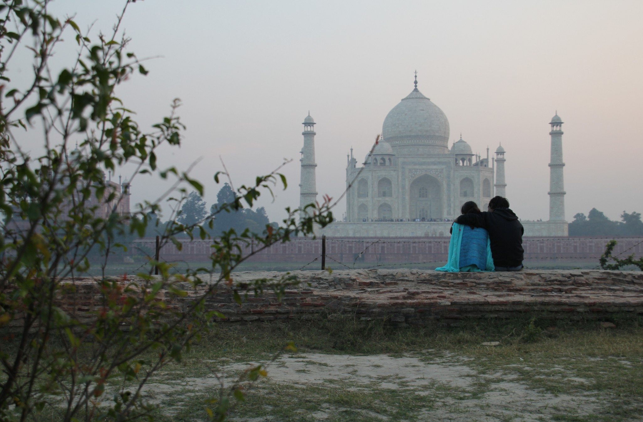 An Indian couple is entranced by the view of the Taj Mahal at sunset from Mehtab Bagh Park in Agra, India.