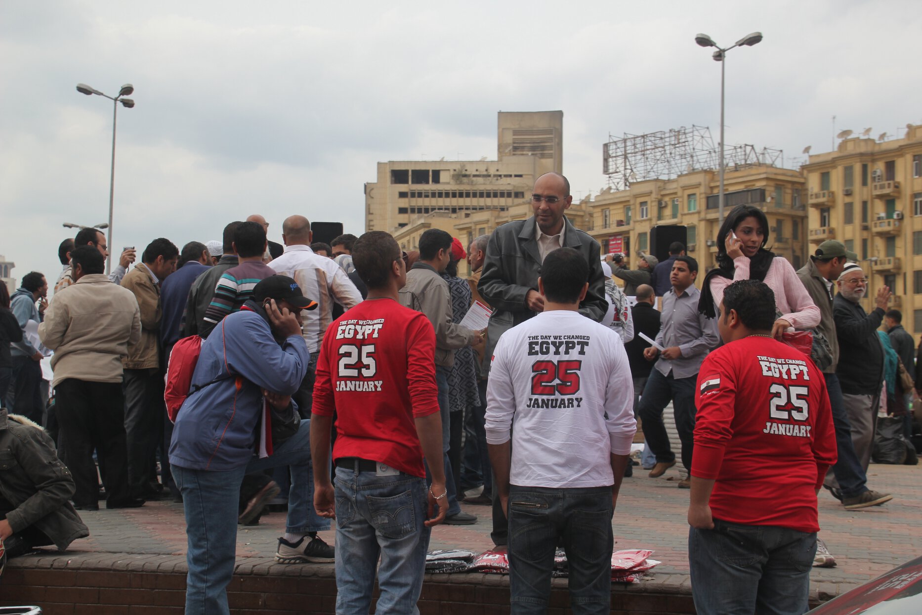 Demonstrators sell "The Day We Changed" T-shirts while protesters gather in Cairo's Tahrir Square.