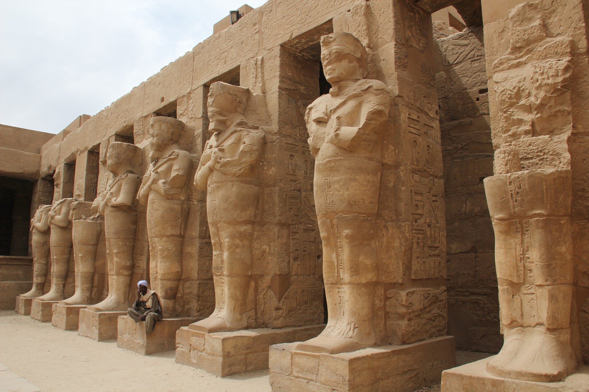An Egyptian man sits in front of the Temple of Ramses III in Karnak's Temple of Amun.