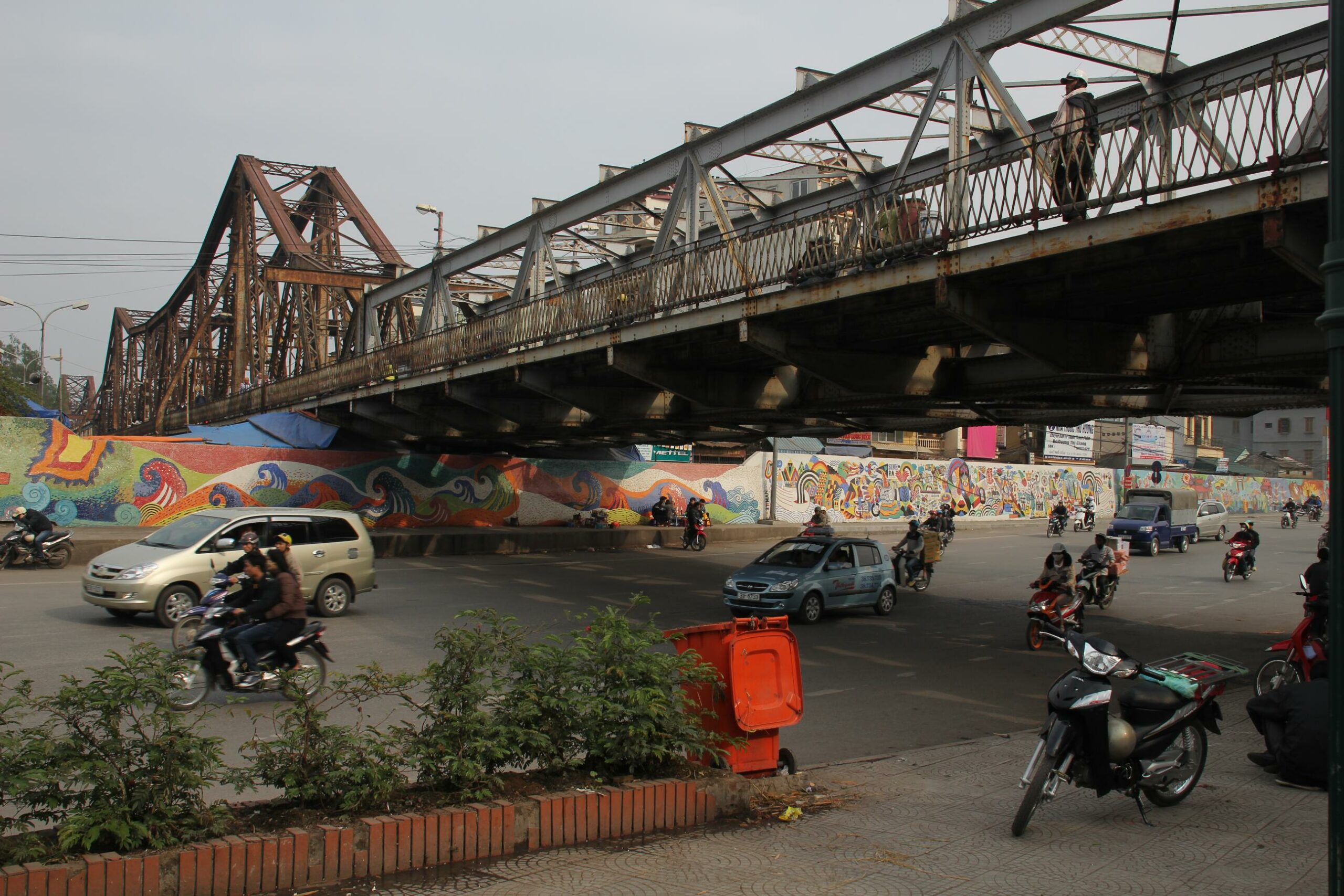 Traffic and a mural pass under Hanoi's historic Long Bien Bridge.