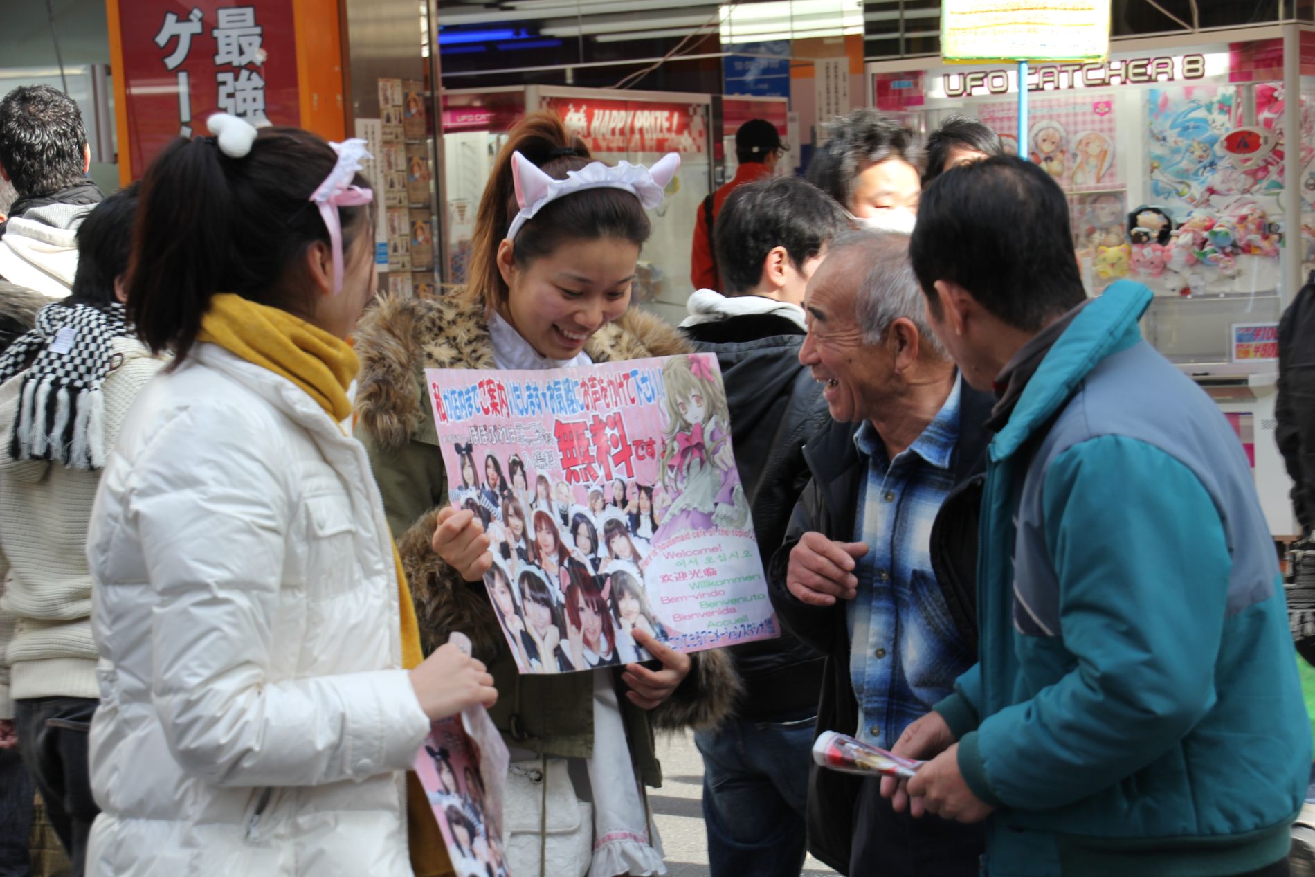 Two Japanese girls dressed as maids with cat ears flirt with men near a maid cafe in Akihabara, Tokyo, Japan.