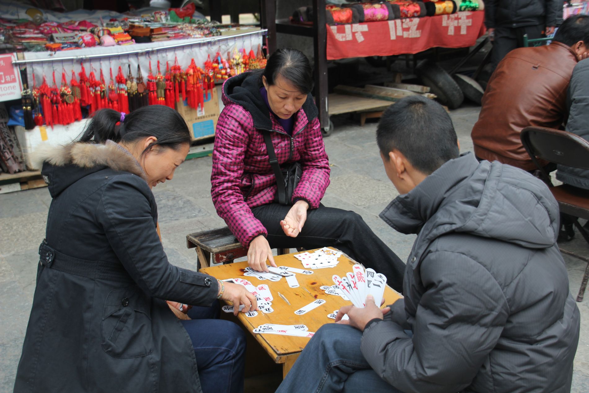 Chinese vendors play cards while waiting for customers in Y&aacute;ngshu&ograve;.