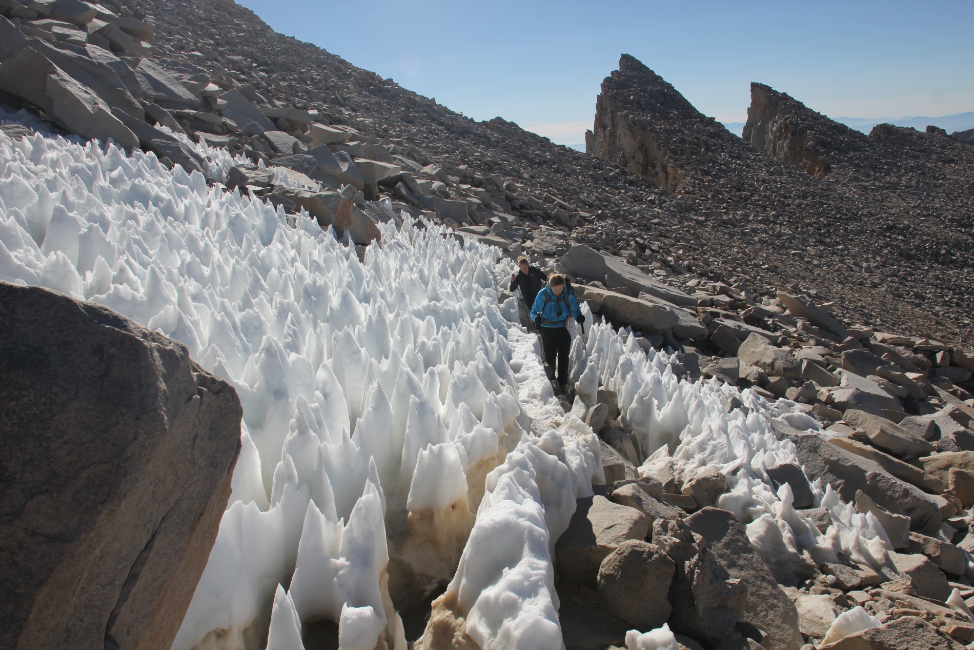 Hikers make their way through a field of snow towers.