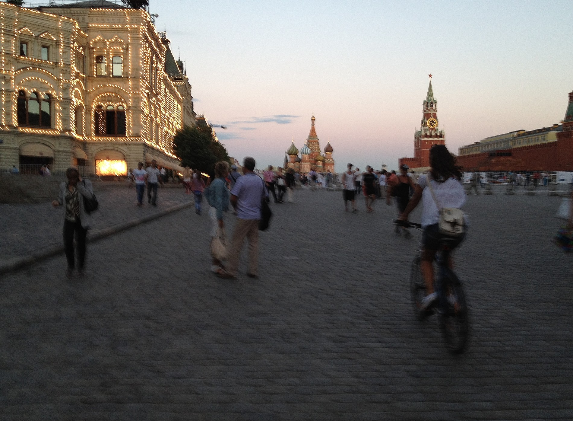 Olya rides her bicycle through Moscow's Red Square at twilight.