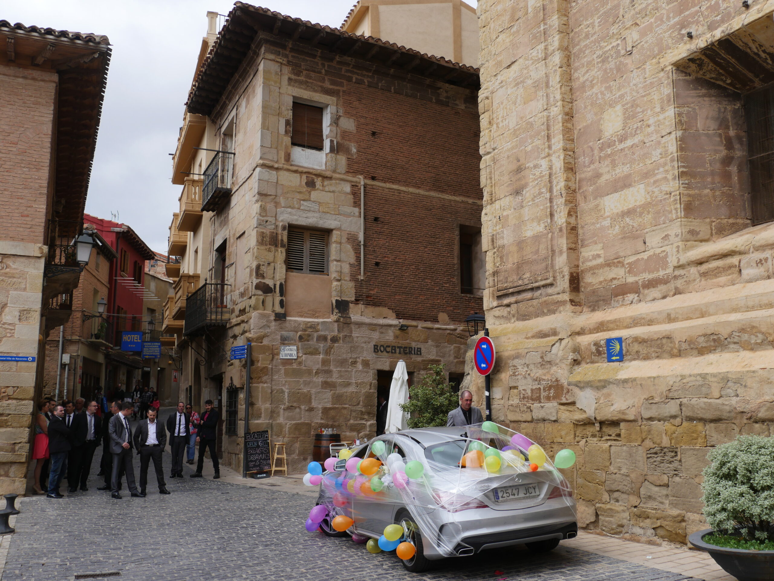 Groomsman and a decorated car sit outside the Iglesia de La Asunci&oacute;n in Navarrete, Spain in preparation for a wedding.