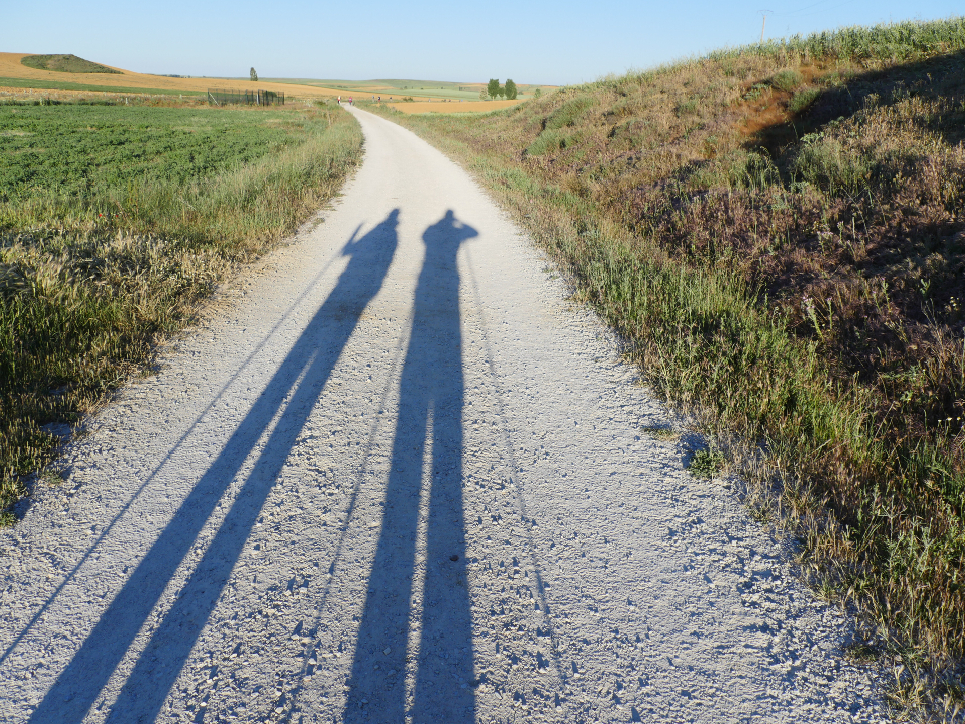 Shadows of two pilgrims appear on a historic Roman road near Mansilla de Las Mulas, Spain.