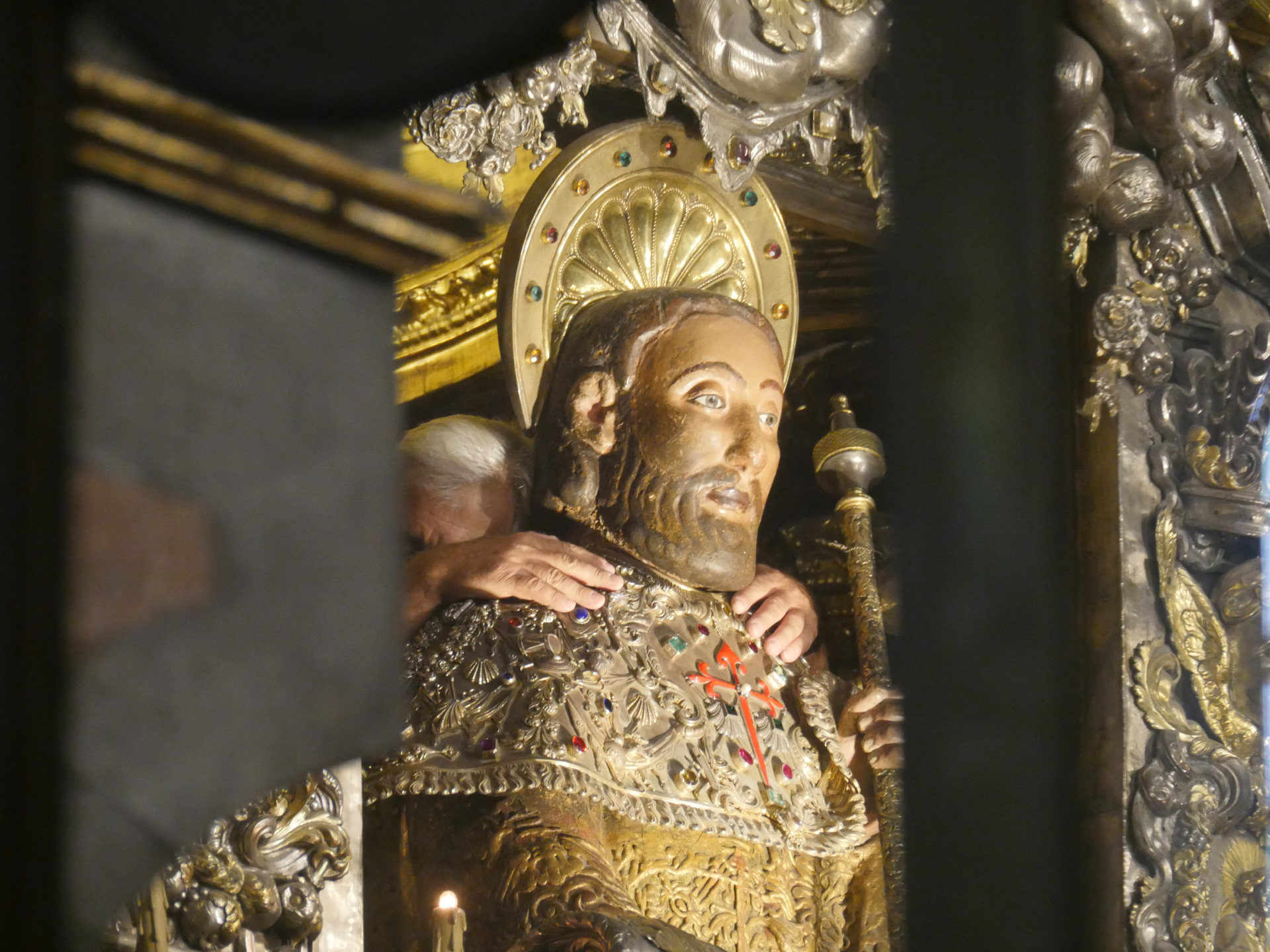 A man hugs the statue of St. James in the Santiago de Compostela Cathedral.