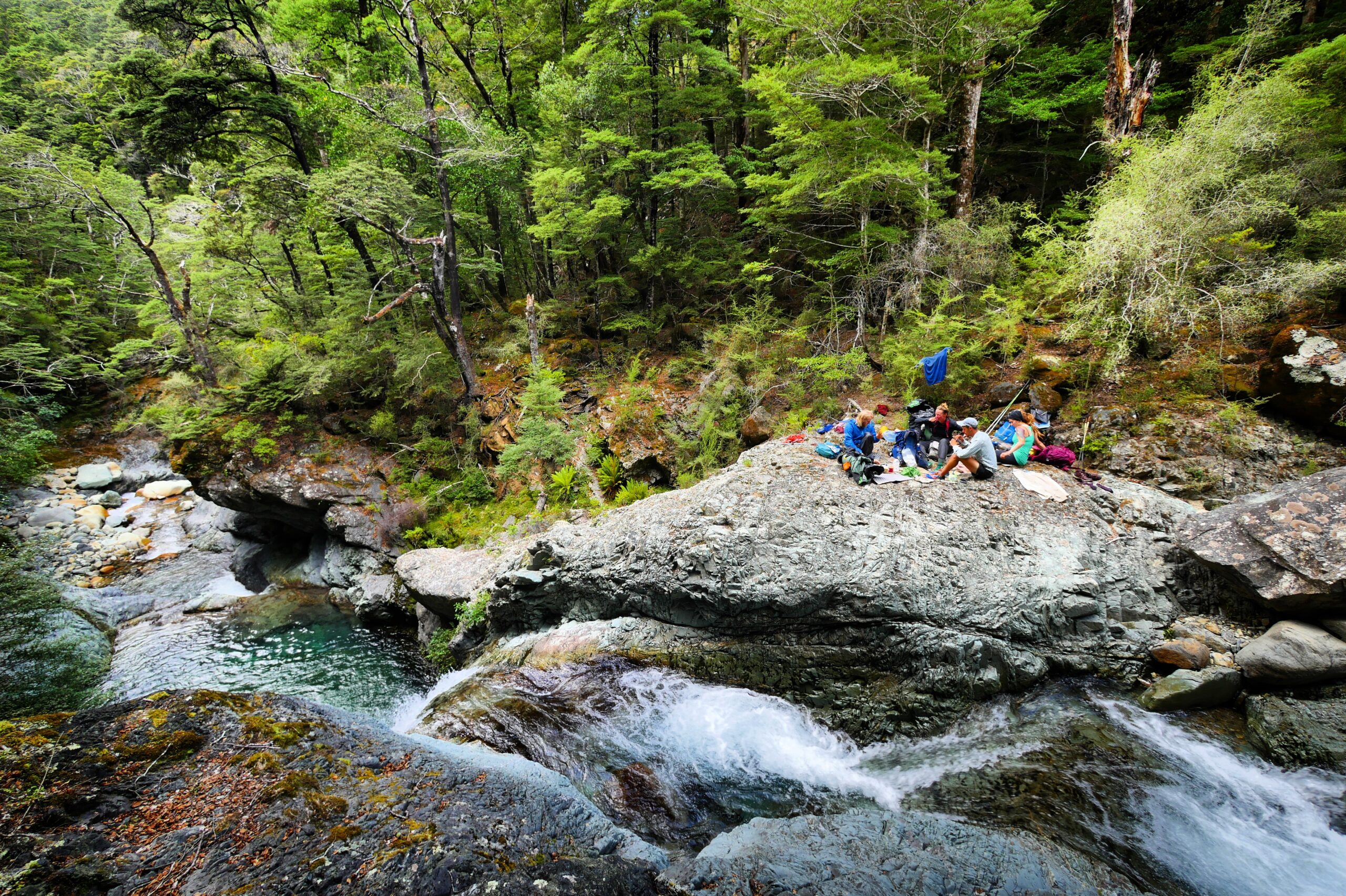 Te Araroa hikers eat lunch amongst waterfalls on the Pelorus River in New Zealand's Richmond Range.