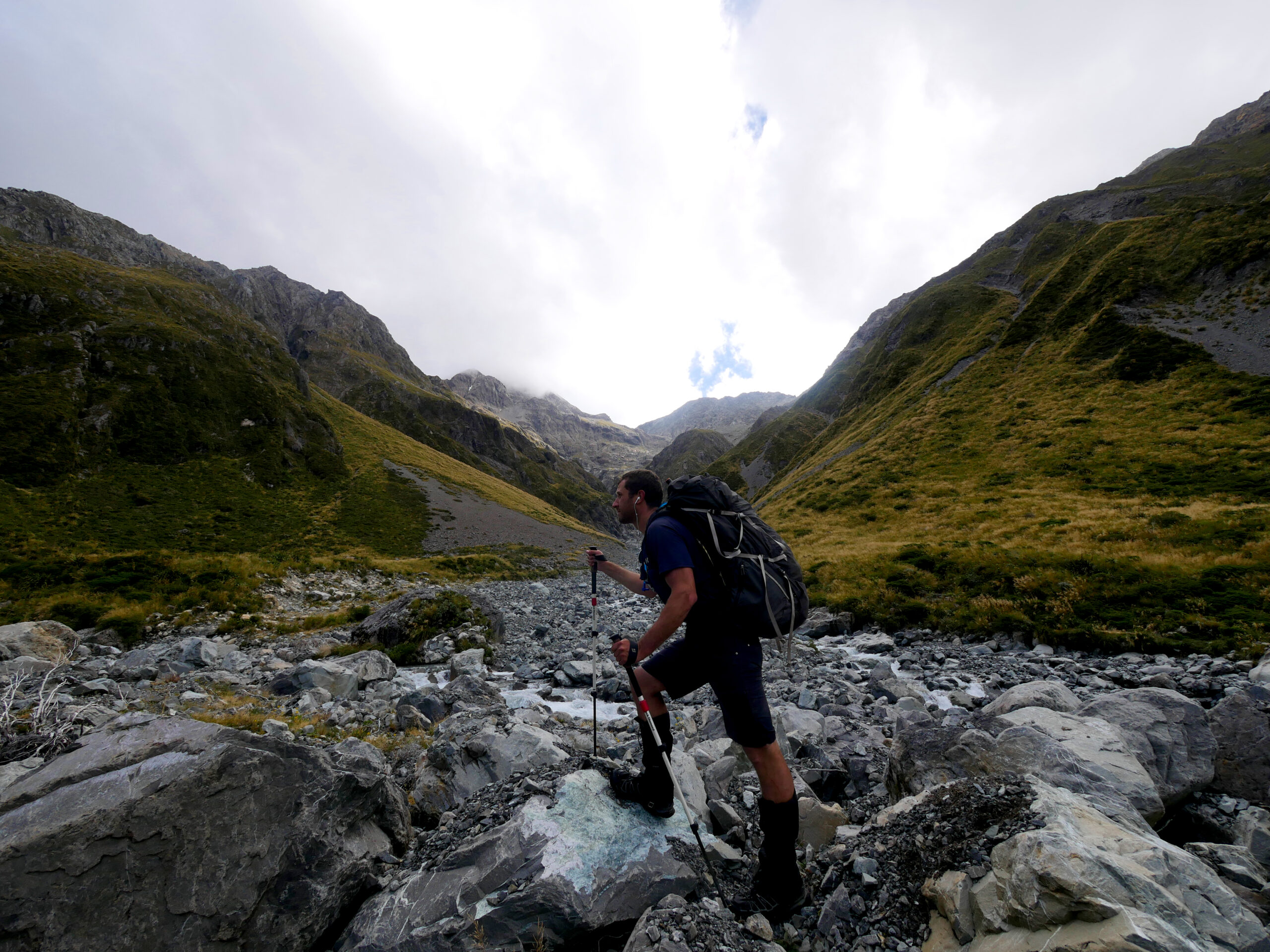 A hiker hikes up Harman Pass toward Whitehorn Pass in Arthur's Pass National Park, New Zealand.