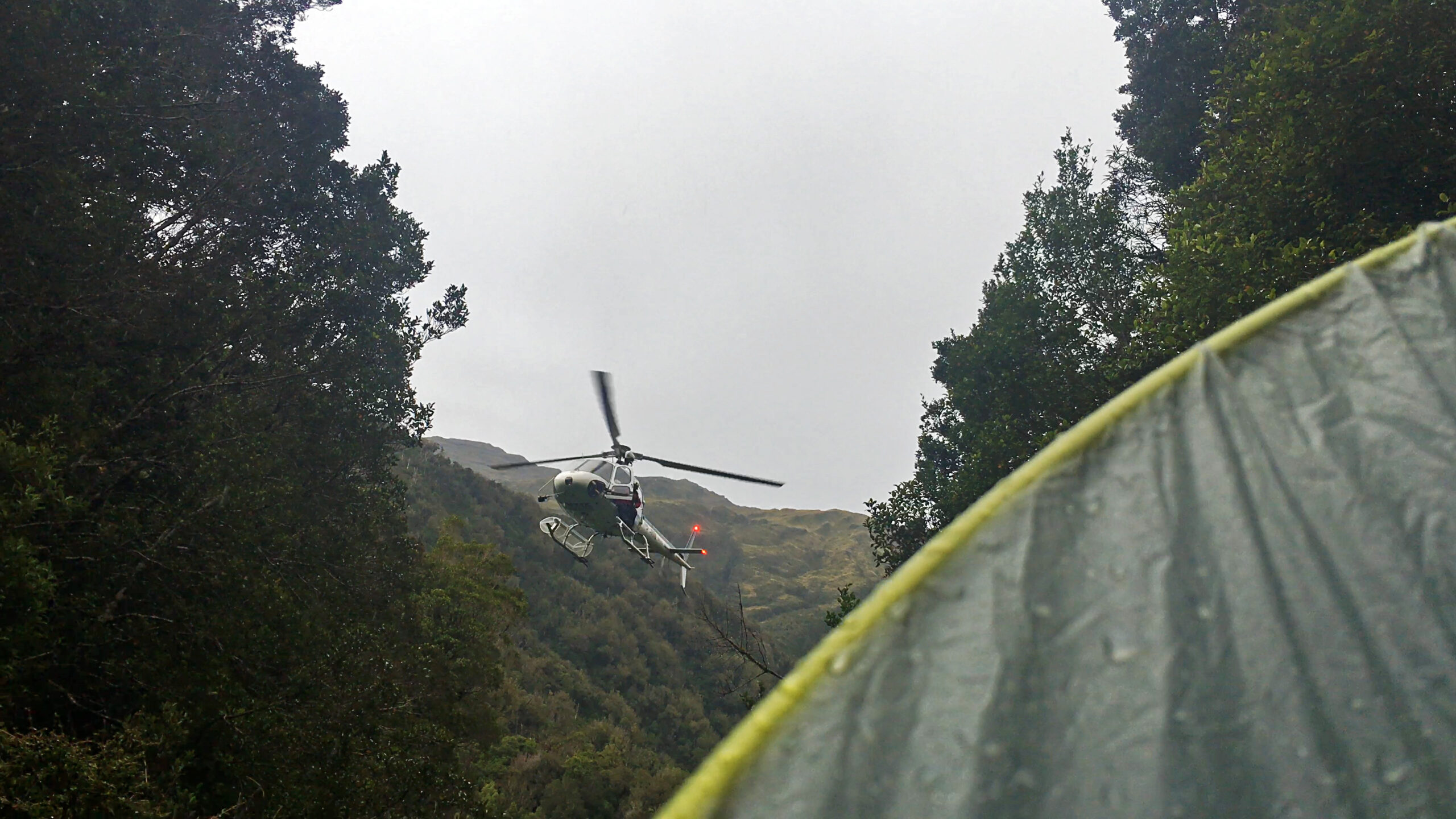 A rescue helicopter hovers above a ravine on the Toaroha Track on New Zealand's South Island.